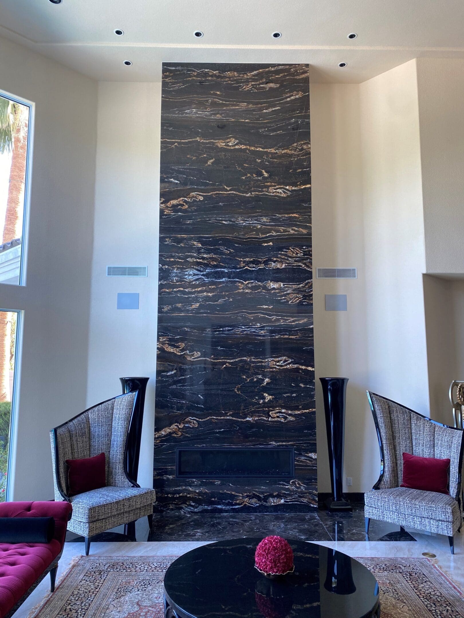 A large black marble wall in the center of two chairs.