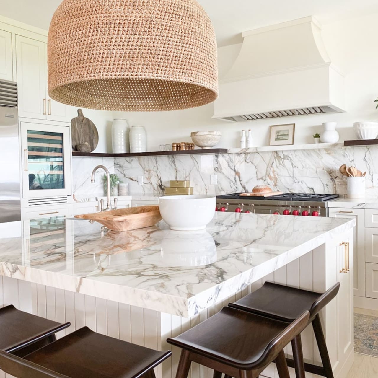 A kitchen with marble counter tops and wooden stools.