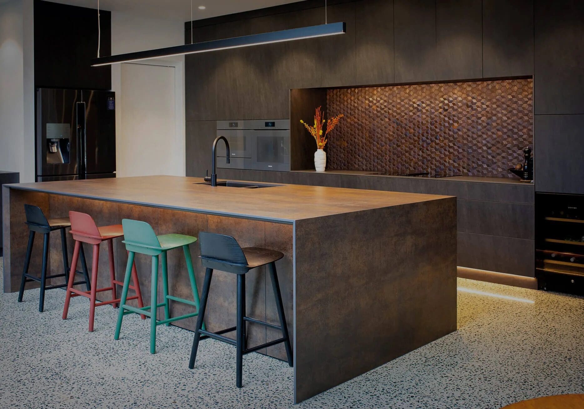 A kitchen with multiple stools and a large counter.