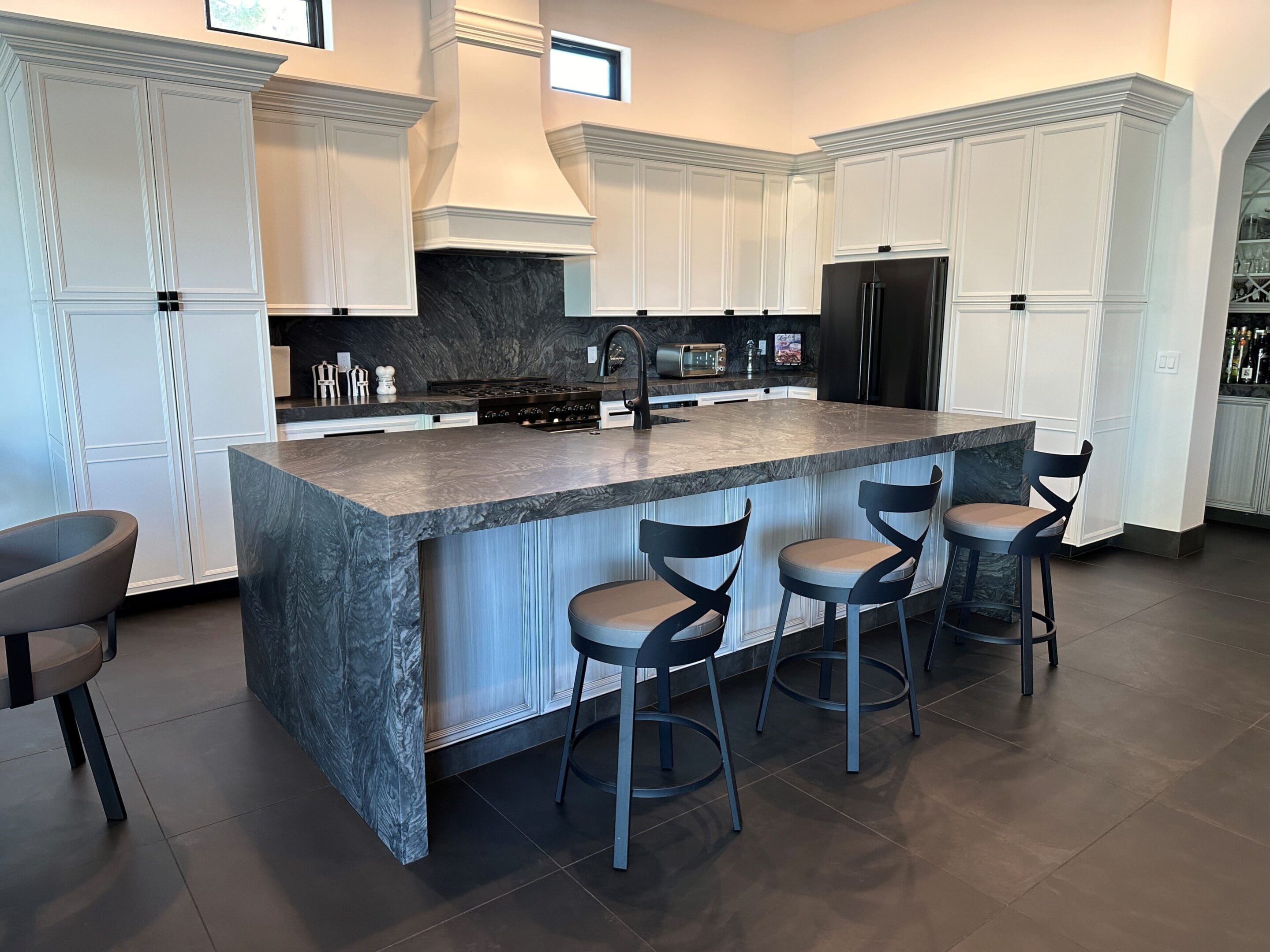 A kitchen with a large island and black stools.