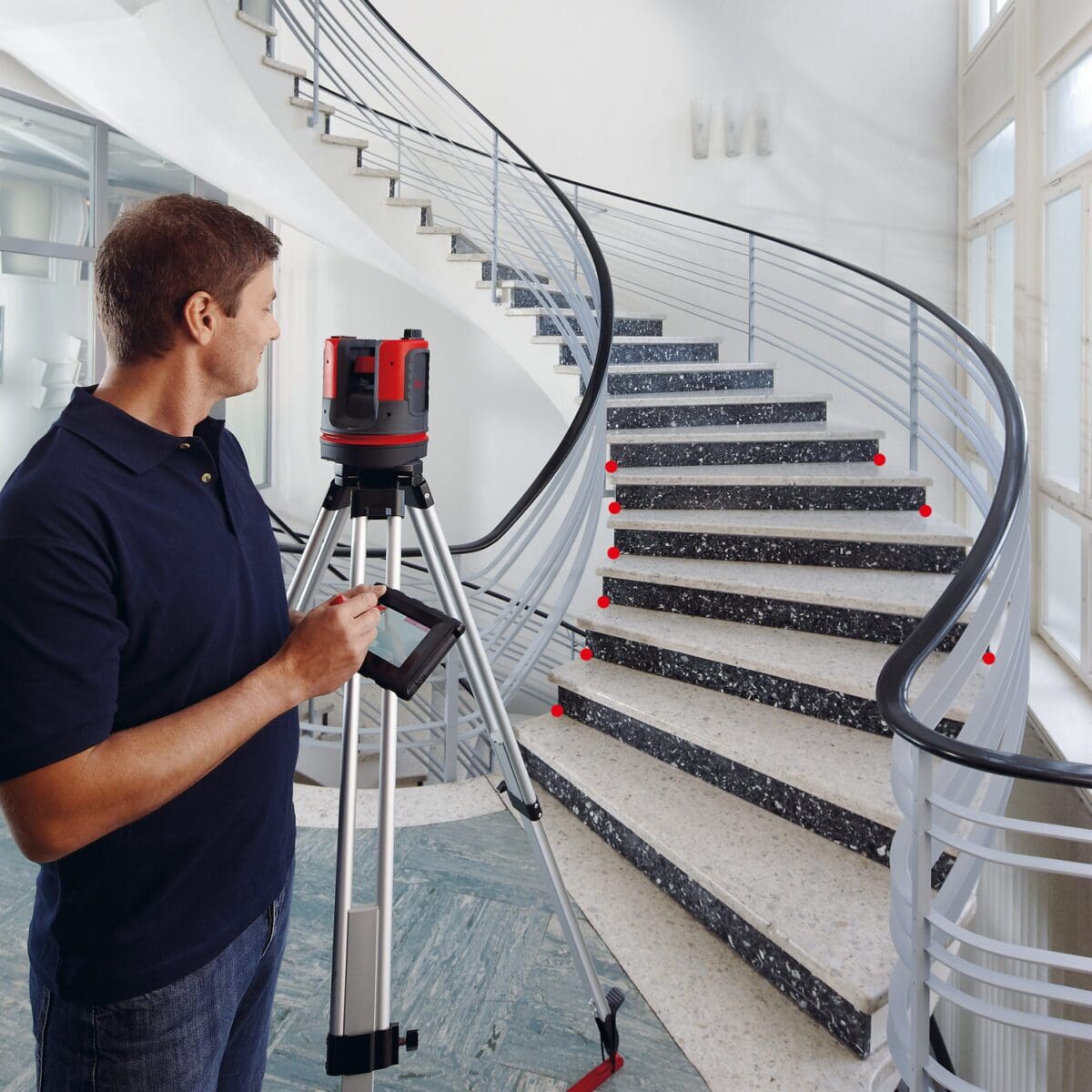 A man holding a camera and tripod near stairs.