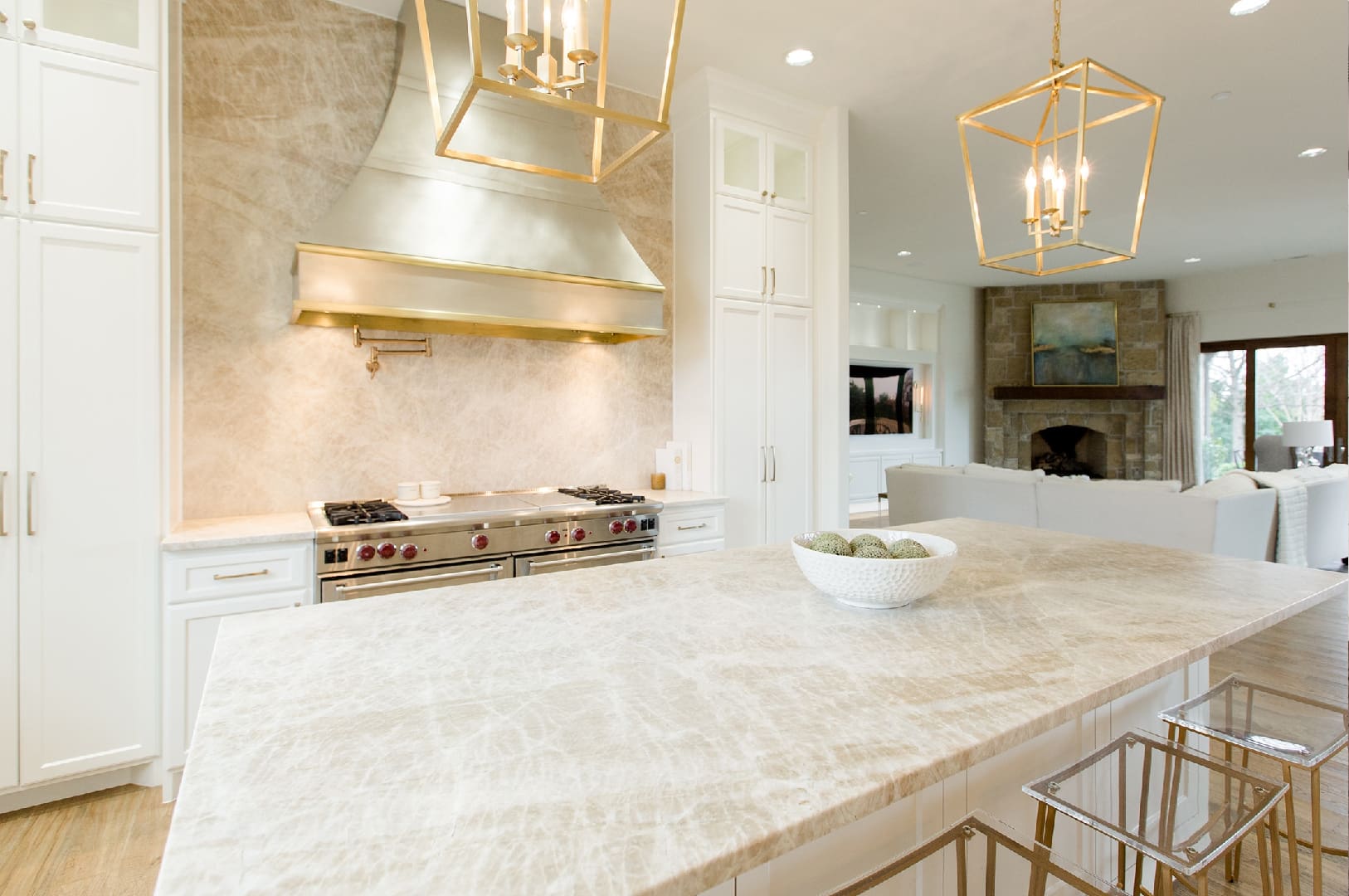 A kitchen with marble counter tops and gold accents.