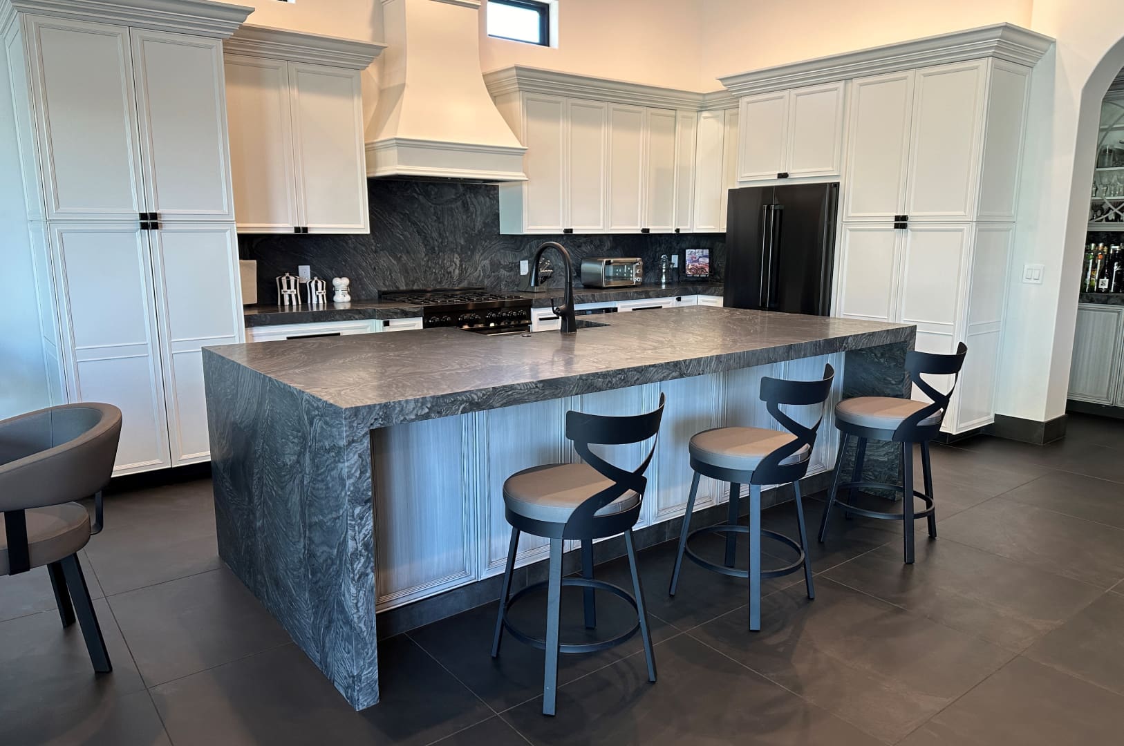 A kitchen with a large island and several stools.