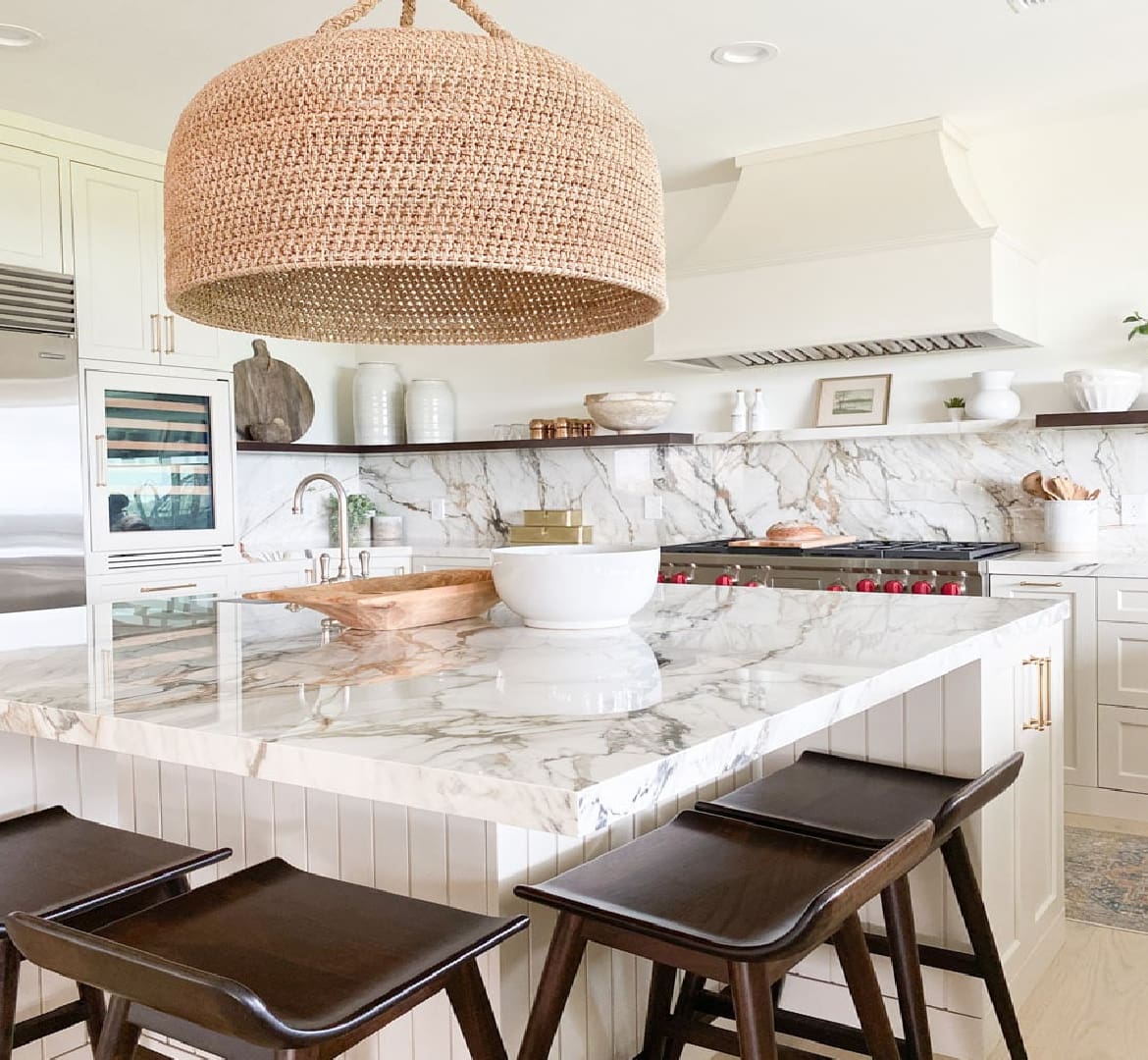 A kitchen with marble counter tops and wooden stools.