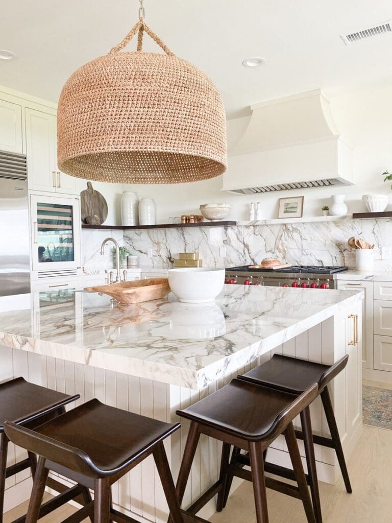 A kitchen with marble counter tops and wooden stools.